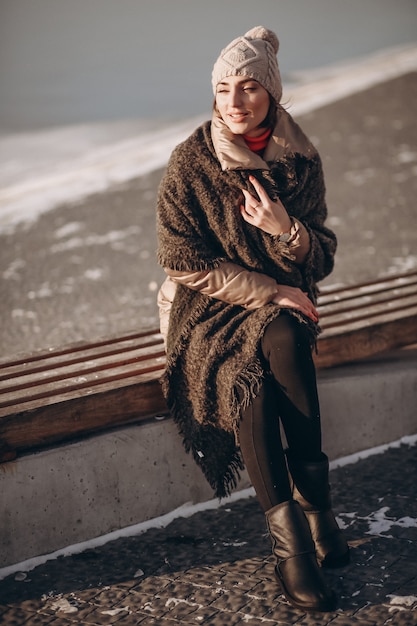 Woman sitting on a bench by the lake in winter