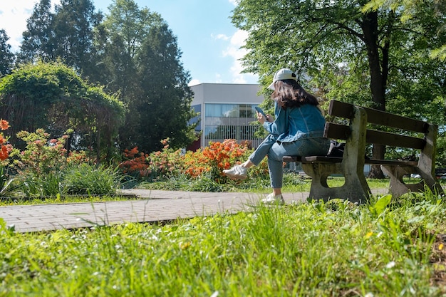 Woman sitting on the bench at city public park reading electronic book