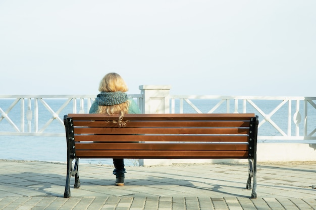 海の素晴らしい景色と堤防のベンチに座っている女性