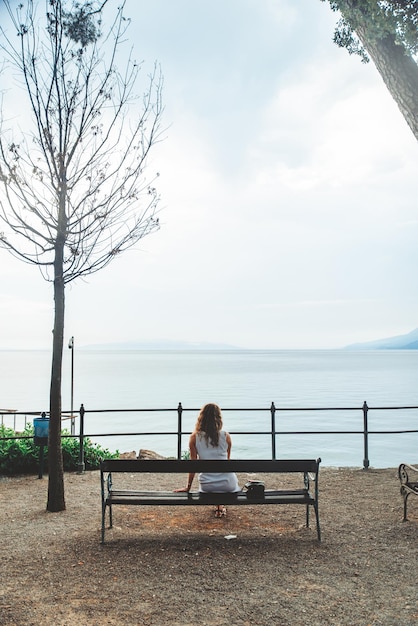 Woman sitting on bench and looking at the sea copy space