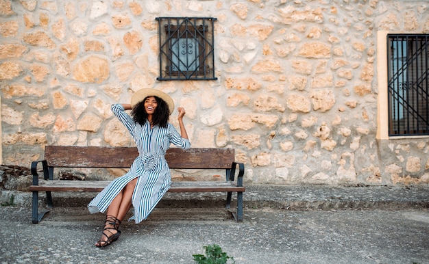 Woman sitting on a bench near a stone house