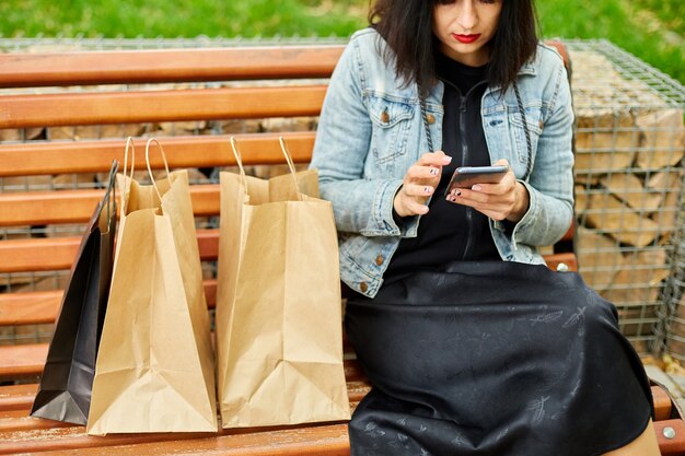 Woman sitting on the bench in the park withpaper shopping bags after shopping