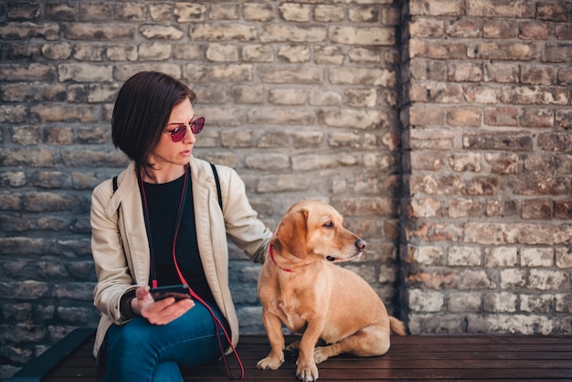 Woman sitting on the bench and petting her dog