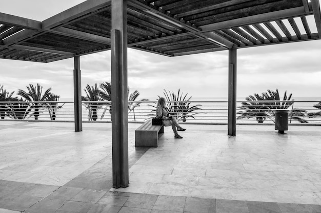 Foto donna seduta su una panchina mentre guarda il mare