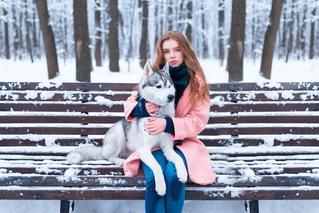 Donna seduta sulla panchina con siberian husky