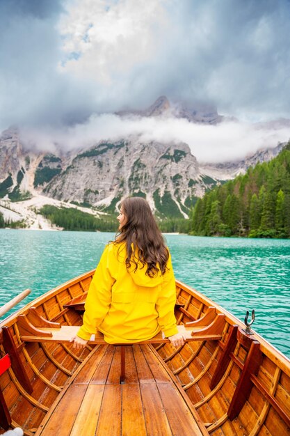 Woman sitting in big brown boat at lago braies lake in cloudy day italy summer vacation in europe