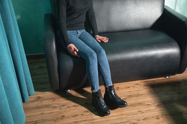 Woman sitting on black leather couch at home