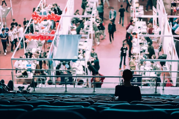 Woman sitting on bleachers looking at exhibition in stadium