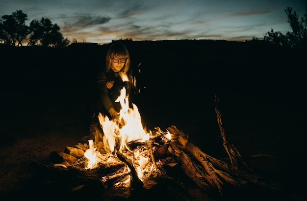 写真 夕暮れの火のそばに座っている女性