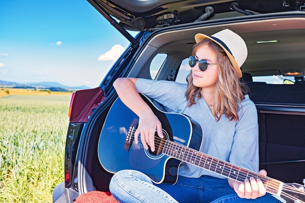woman sitting by guitar on field