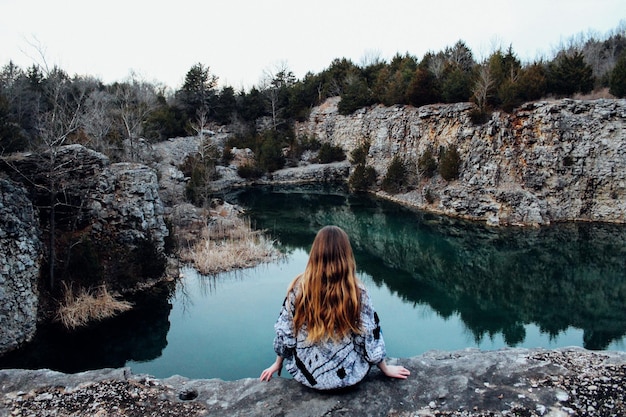 Foto donna seduta vicino al lago contro un cielo limpido