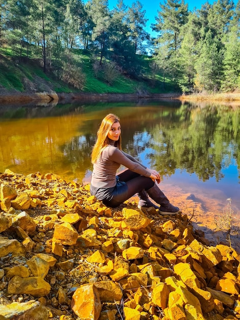 Woman sitting by lake during autumn