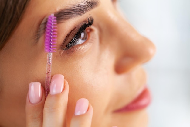 Photo woman sitting by the mirror and applying makeup