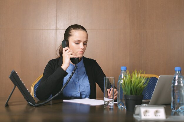 Woman sitting by the table with laptop in office