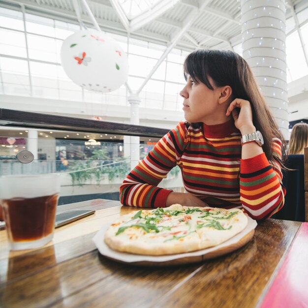 Woman sitting in cafe pizza in front