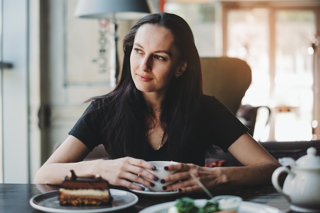 Woman sitting in cafe with cup of coffee and smiling