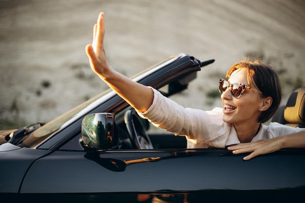 Woman sitting in car cabriolet and waving hands