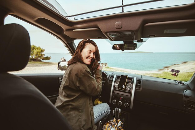 Woman sitting in car relaxed and looking at sea beach summer vacation