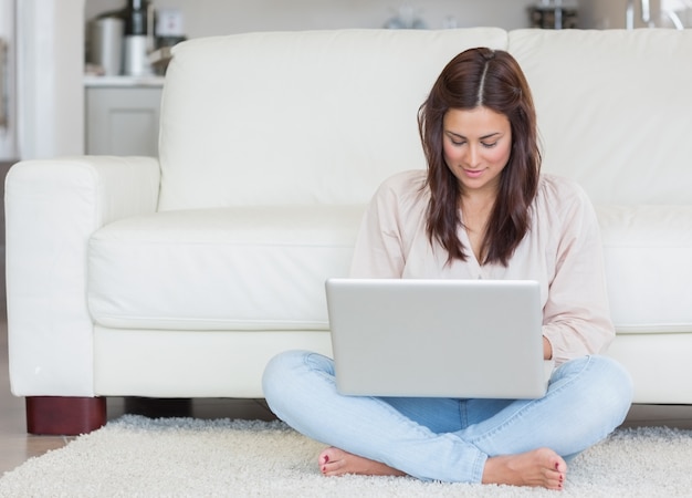 Donna che si siede sul tappeto con il suo laptop