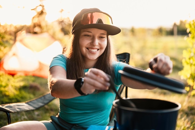 Woman sitting in chairs outside the tent sunset camping in\
forest recreation outdoor activity cooking dinner with camping gear\
in camp summer travel outdoor adventure