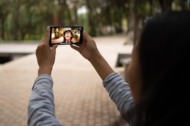 Woman sitting in city park and using phone for video call