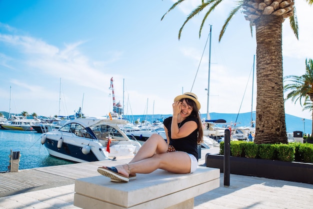 Woman sitting at city pier and looking on yachts