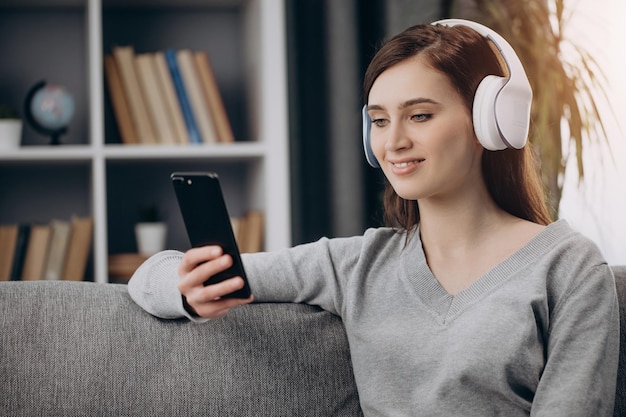 ヘッドフォンでソファに座って音楽を聴く女性