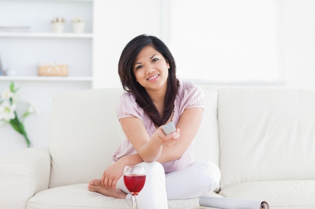 Женщина, сидящая на диване и держащая телевизионный пульт