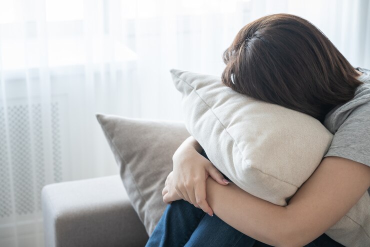 Photo ソファに座って、枕、孤独、悲しみの概念を抱き締める女性
