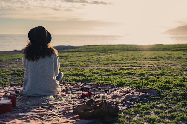 Photo woman sitting on coverlet on grass