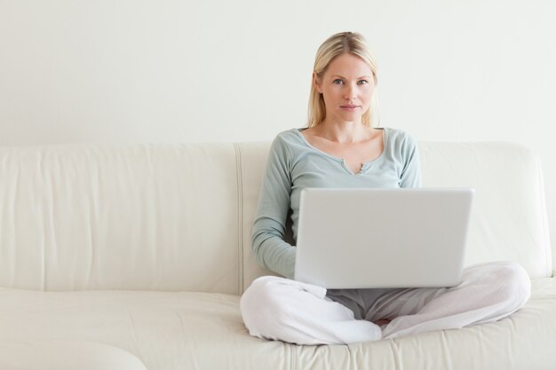 Woman sitting cross legged on the sofa with her notebook