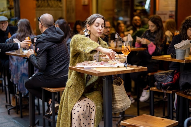 Woman sitting on crowded street at bar or restaurant outdoors