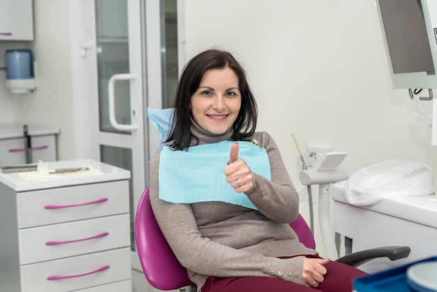 Woman sitting in dentist chair showing thumb up