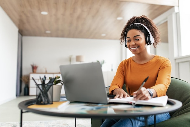 Woman sitting at desk using computer and writing in notebook