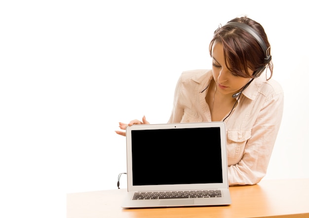 Woman sitting at a desk wearing a headset looking at the blank screen on her laptop