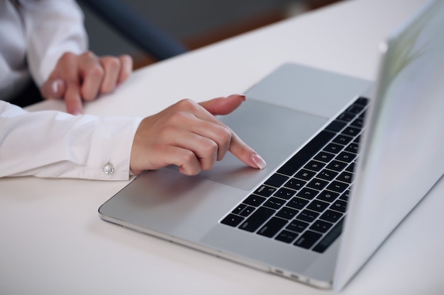 Woman sitting at desk and working at computer hands close up