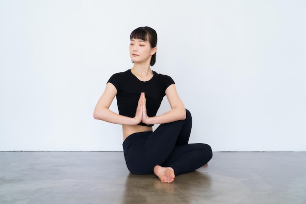 座って、黒い服を着て屋内でヨガをしている女性