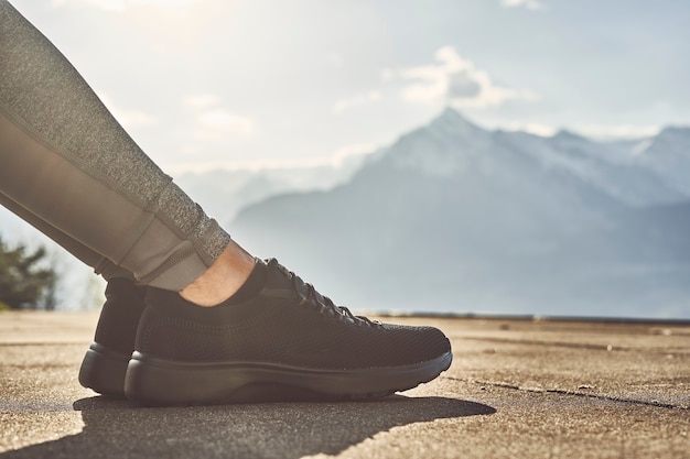 Woman sitting down in the evening at sunny mountains trainers close up