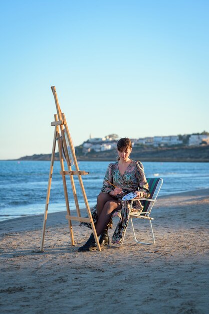 Woman sitting at an easel painting by the seashore