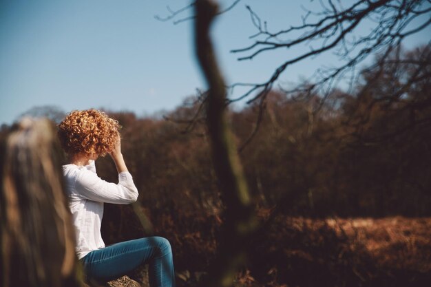 Photo woman sitting on field against clear sky