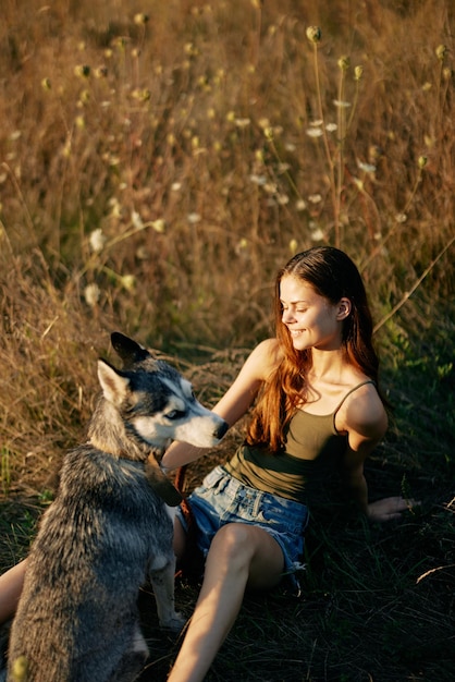 Photo woman sitting in a field with a dachshund dog smiling while spending time in nature with a friend dog in autumn at sunset high quality photo