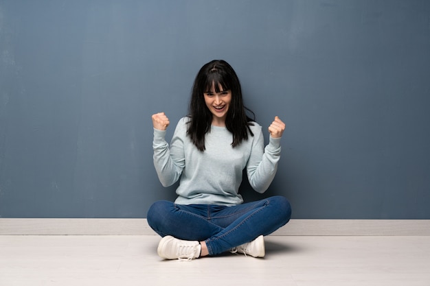 Woman sitting on the floor celebrating a victory in winner position