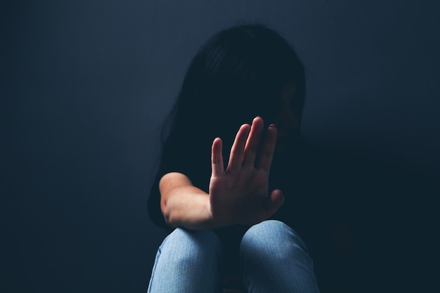 Woman sitting on the floor covering her face sad