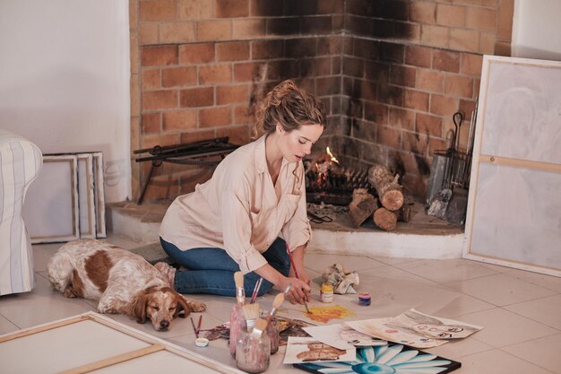 Woman sitting on floor and drawing and dog sleeping near