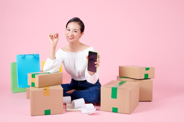 Woman sitting on floor showing cell phone with blank screen for promotion of delivery service