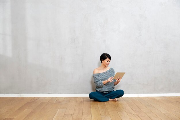 Woman sitting on floor using tablet