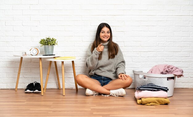 洋服バスケットを持って床に座っている女性