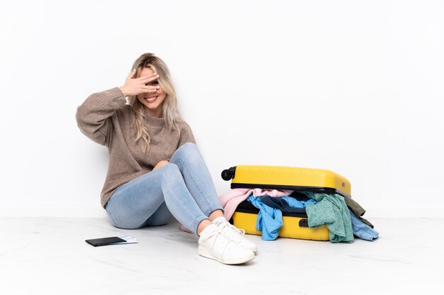 Woman sitting on the floor with suitcase over isolated wall