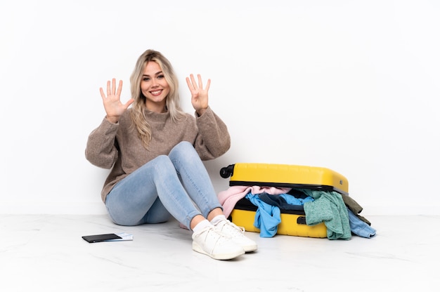 Woman sitting on the floor with suitcase over isolated wall