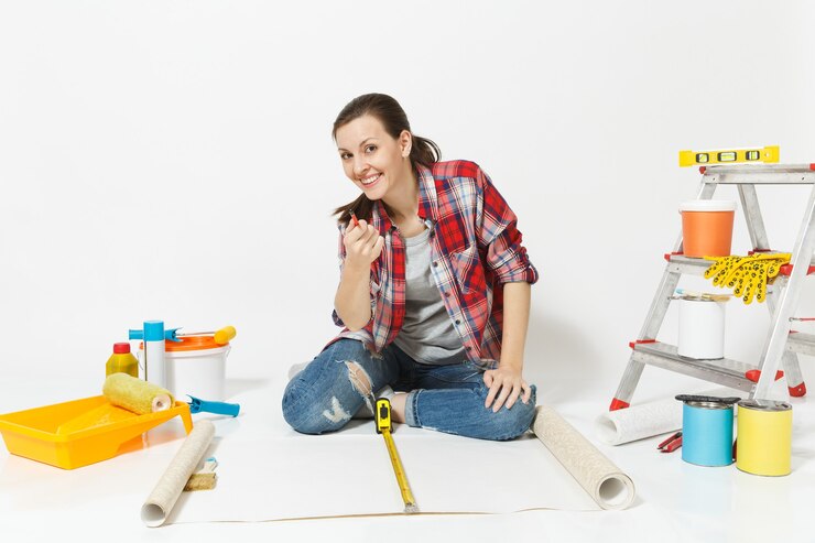 फोटो woman sitting on floor with wallpaper rolls, measure tape, instruments for renovation apartment isolated on white background. accessories for gluing, painting tools. repair home concept. copy space.